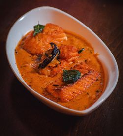 Chicken tikka masala served in a white oval dish with creamy orange sauce and garnished with herbs and spices.