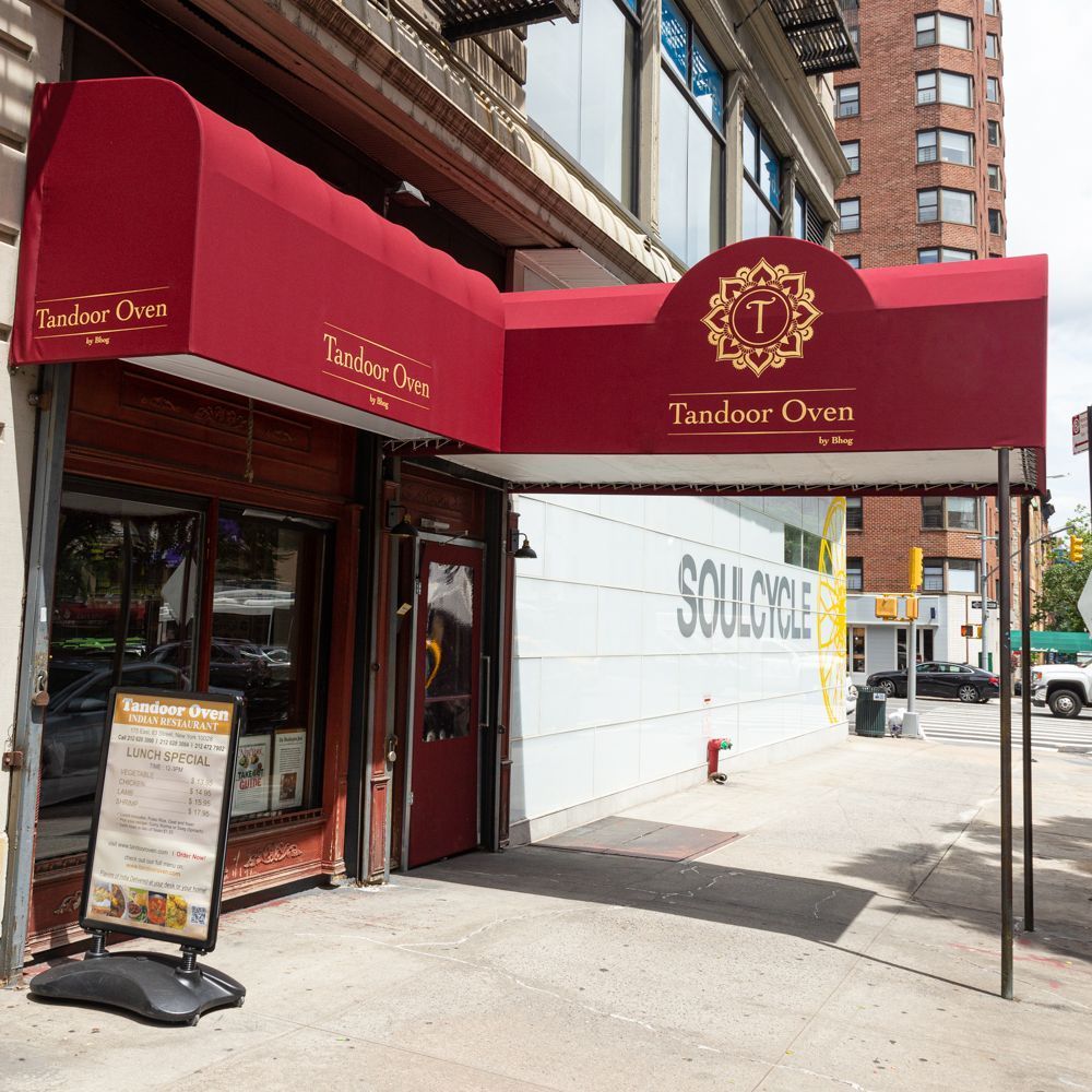 Tandoor Oven entrance with red awning and sidewalk sign showing lunch special menu on a city street.