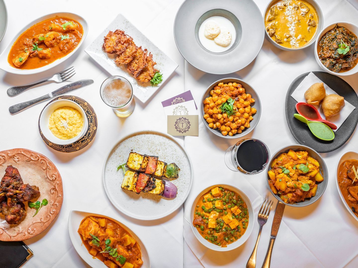 Indian cuisine spread featuring chicken tikka masala, palak paneer, and garlic naan, served with wine at Tandoor Oven